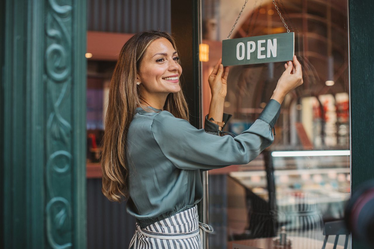 Small-business-owner-putting-open-sign-on-door